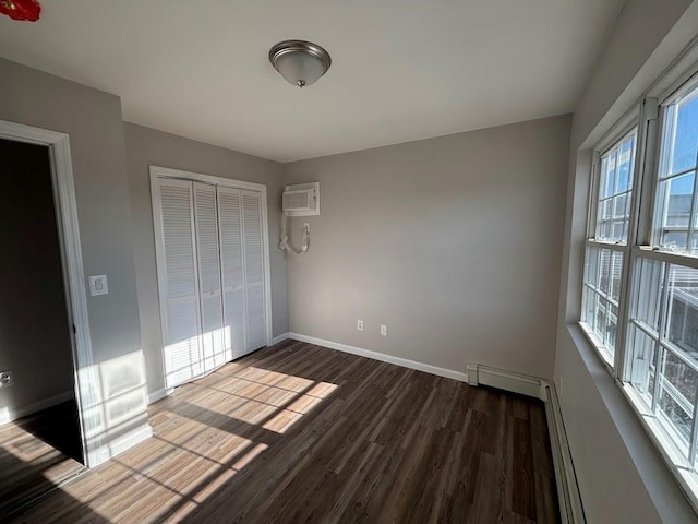 unfurnished bedroom featuring dark hardwood / wood-style floors, a closet, and an AC wall unit