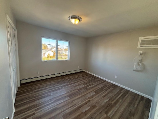 unfurnished bedroom with a baseboard heating unit, a wall unit AC, dark hardwood / wood-style floors, and a closet