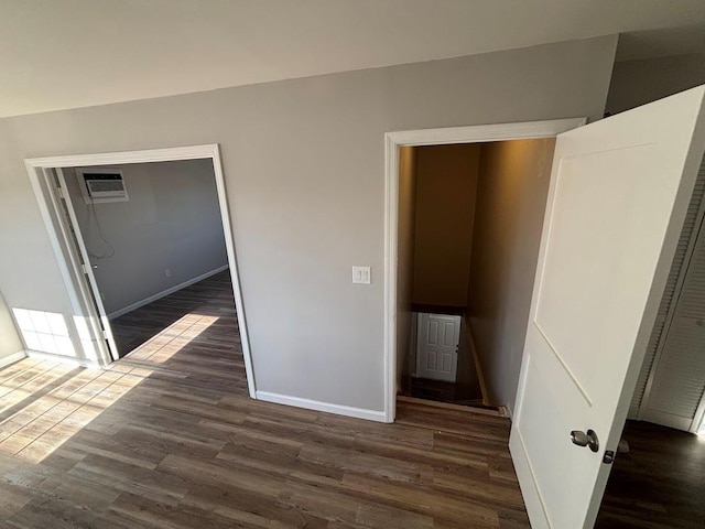 unfurnished bedroom with a wall mounted AC, dark hardwood / wood-style flooring, and a closet