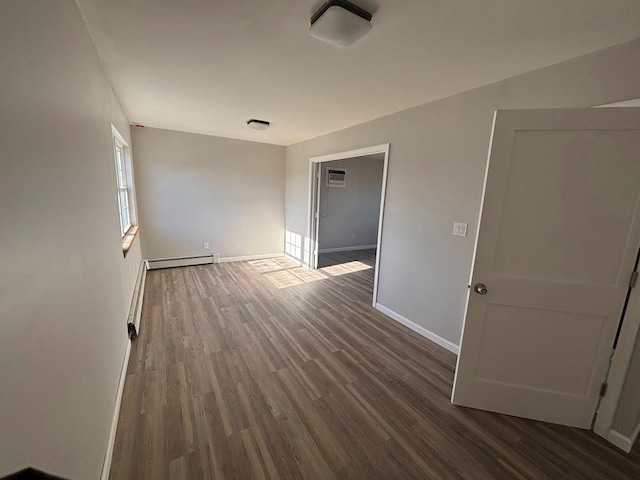 unfurnished room featuring dark wood-type flooring and a baseboard radiator