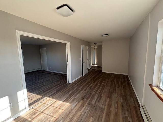 unfurnished room with dark hardwood / wood-style flooring and a baseboard heating unit