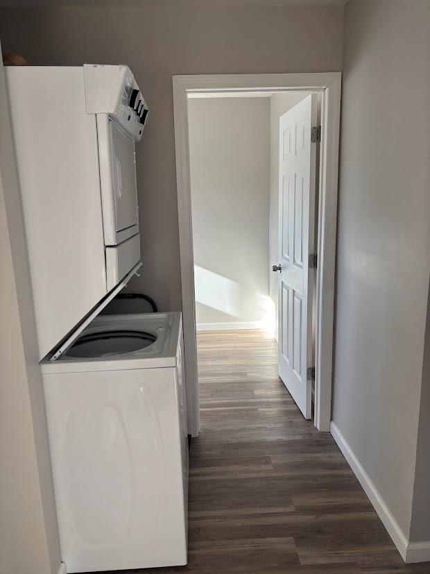 clothes washing area featuring dark wood-type flooring and stacked washer and clothes dryer