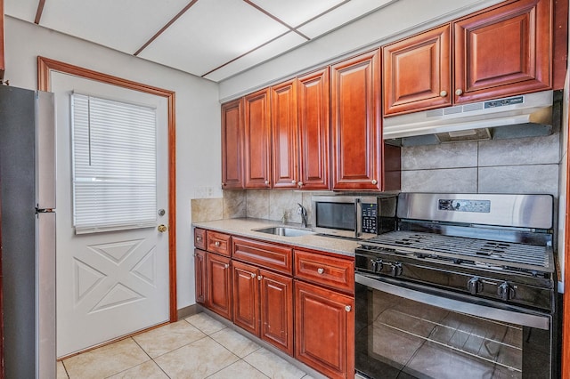 kitchen featuring sink, a drop ceiling, tasteful backsplash, light tile patterned flooring, and appliances with stainless steel finishes