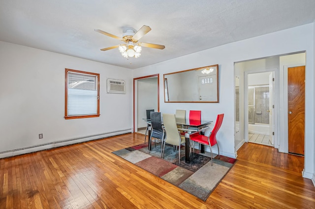 dining room with baseboard heating, ceiling fan, wood-type flooring, and a wall mounted air conditioner