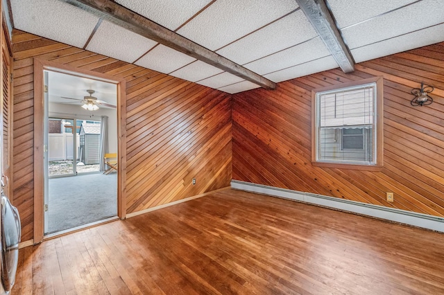 bonus room featuring ceiling fan, beam ceiling, wooden walls, and a baseboard radiator