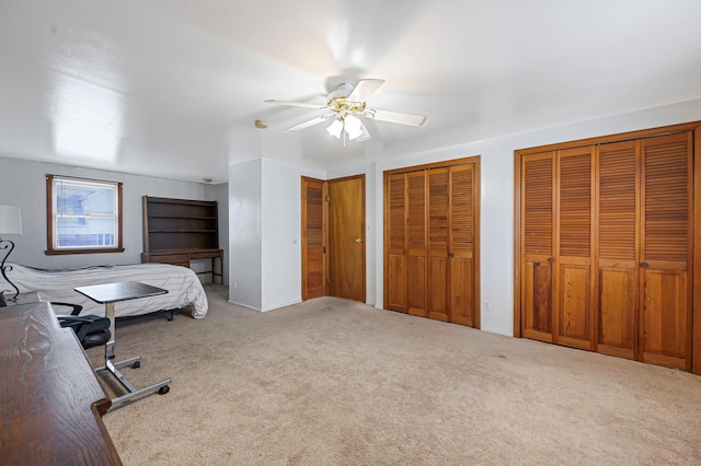 carpeted bedroom featuring two closets and ceiling fan