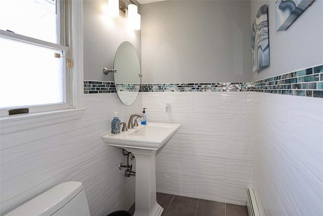 bathroom with tile patterned flooring, toilet, tile walls, and a baseboard heating unit