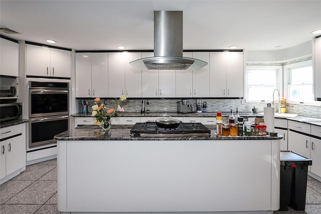 kitchen with sink, stainless steel appliances, a kitchen island, island exhaust hood, and white cabinets