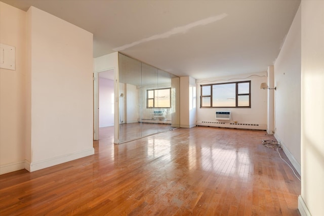 unfurnished room featuring light hardwood / wood-style floors, a baseboard heating unit, and a wall mounted AC