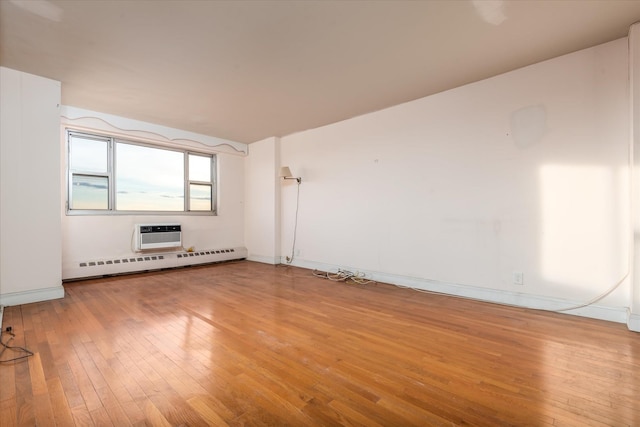 unfurnished room with a baseboard radiator, a wall mounted air conditioner, and wood-type flooring