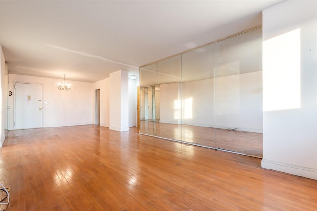 spare room with light hardwood / wood-style flooring and an inviting chandelier