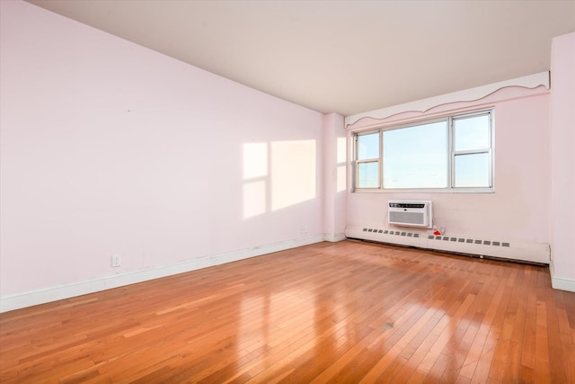 spare room featuring vaulted ceiling, a baseboard radiator, a wall unit AC, and hardwood / wood-style flooring