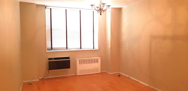 spare room featuring radiator heating unit, heating unit, an inviting chandelier, and hardwood / wood-style floors