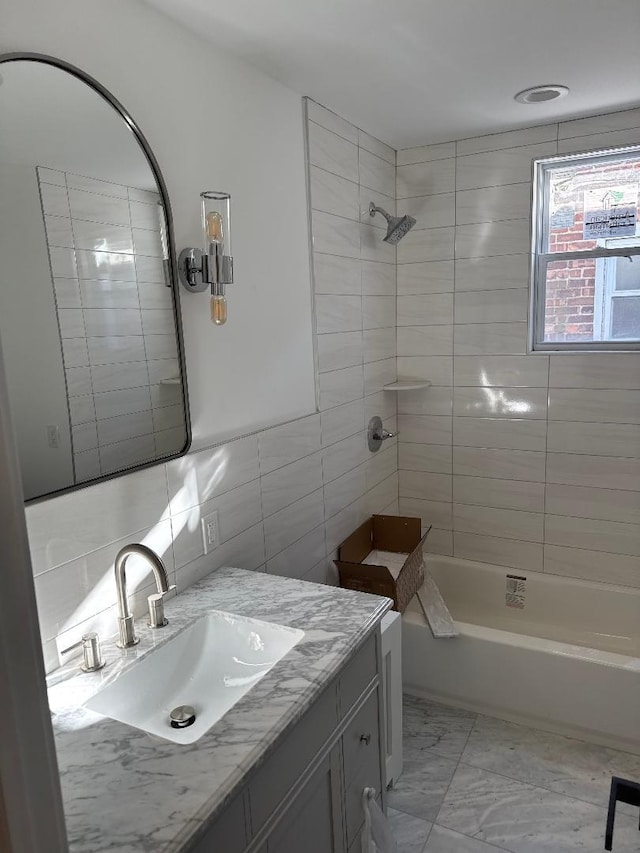 bathroom featuring vanity, decorative backsplash, tiled shower / bath combo, and tile walls