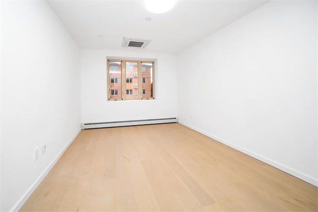 spare room with baseboard heating and light hardwood / wood-style flooring