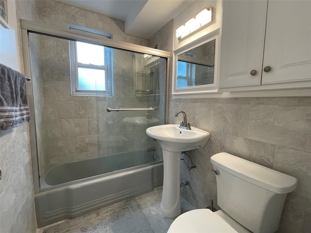 bathroom with toilet, tiled shower / bath, and tile walls