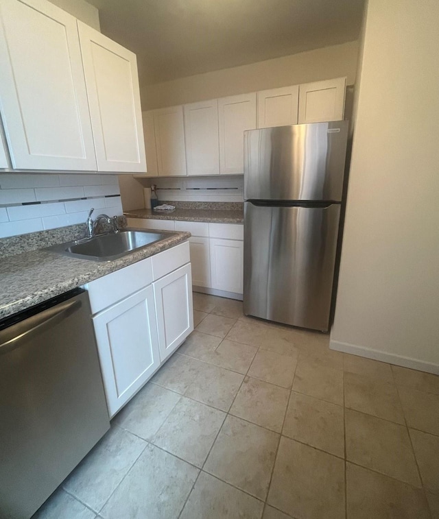 kitchen featuring appliances with stainless steel finishes, light tile patterned floors, white cabinetry, and sink