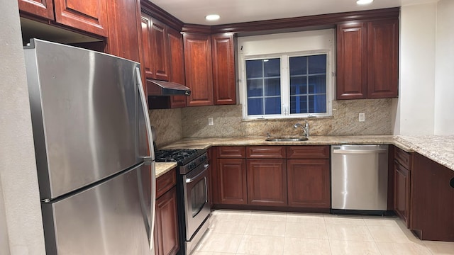 kitchen featuring light stone countertops, appliances with stainless steel finishes, backsplash, and sink