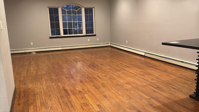 unfurnished room featuring wood-type flooring and a baseboard radiator