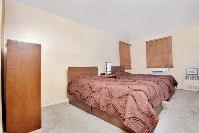 bedroom with light colored carpet, a wall mounted air conditioner, and radiator