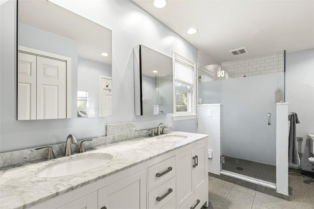 bathroom featuring tile patterned flooring, a sink, visible vents, and a shower stall