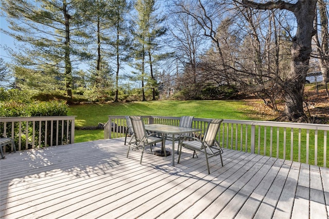 wooden deck featuring outdoor dining area and a lawn