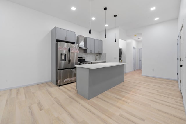 kitchen with appliances with stainless steel finishes, tasteful backsplash, wall chimney range hood, decorative light fixtures, and gray cabinets