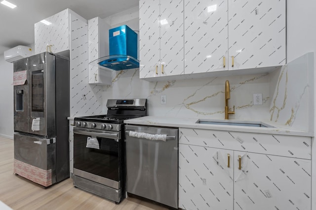 kitchen featuring light stone countertops, sink, wall chimney exhaust hood, stainless steel appliances, and light hardwood / wood-style flooring