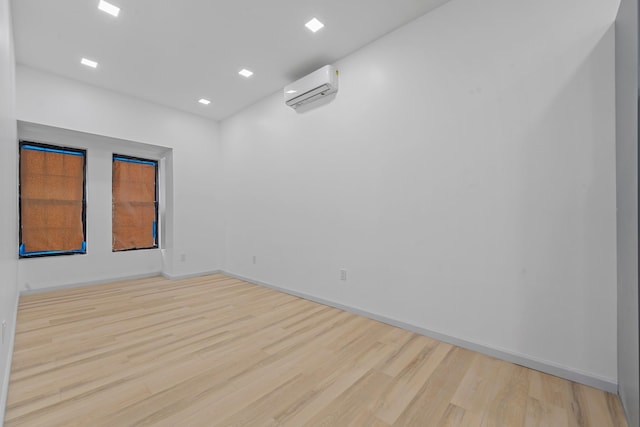 unfurnished room with a wall mounted air conditioner and light hardwood / wood-style flooring