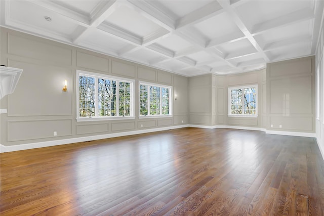 spare room featuring wood-type flooring, beamed ceiling, and a healthy amount of sunlight