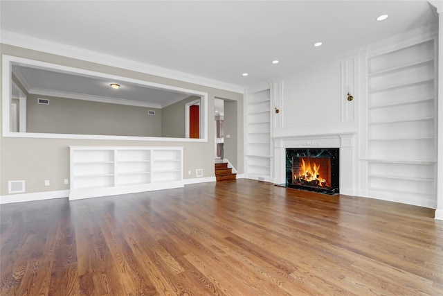 unfurnished living room featuring ornamental molding, a high end fireplace, built in features, and wood-type flooring