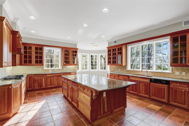 kitchen with sink, tasteful backsplash, stone countertops, a center island, and ornamental molding