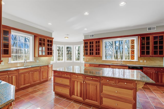 kitchen featuring tasteful backsplash, a center island, sink, and light tile patterned floors