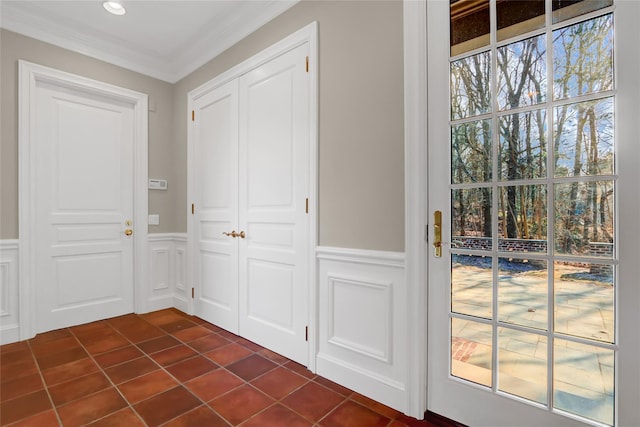 doorway with ornamental molding, plenty of natural light, and dark tile patterned flooring