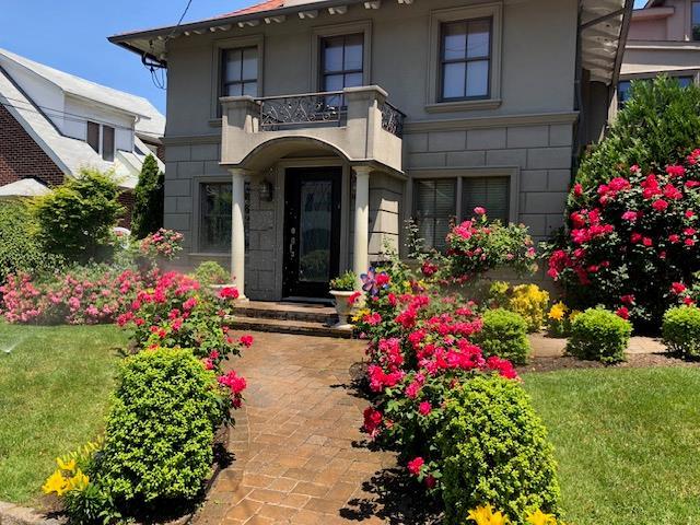 entrance to property featuring a balcony and a yard