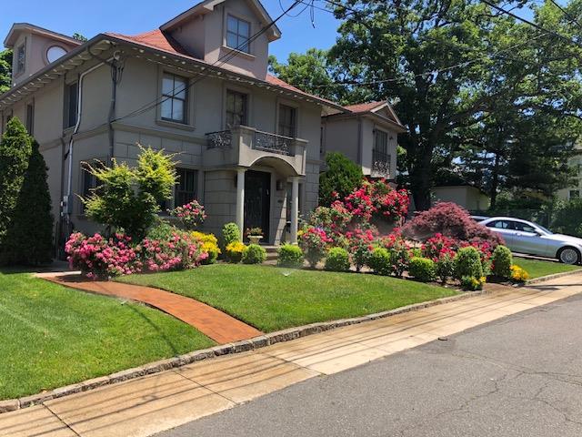 view of front of house featuring a balcony and a front lawn