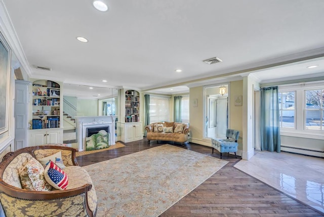 living room featuring hardwood / wood-style floors, crown molding, a baseboard radiator, and built in features