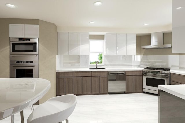 kitchen featuring sink, white cabinetry, appliances with stainless steel finishes, decorative backsplash, and wall chimney range hood