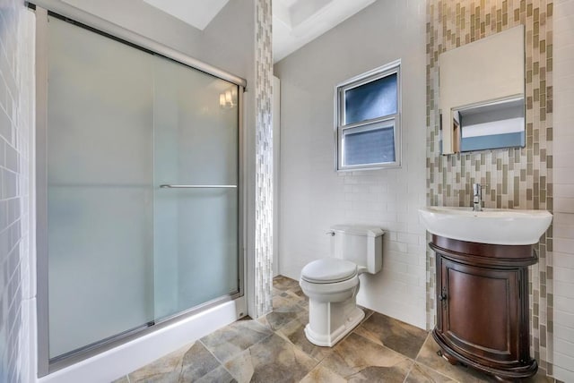 bathroom featuring vanity, toilet, a shower with door, and tile walls