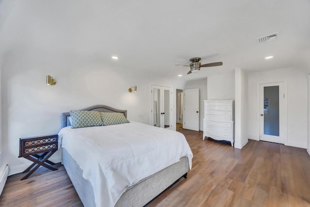 bedroom featuring wood-type flooring, a baseboard radiator, and ceiling fan