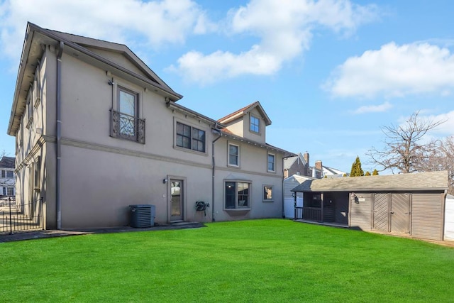 back of property with an outdoor structure, central AC unit, and a lawn