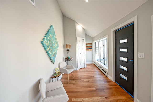 entryway featuring lofted ceiling, light wood-type flooring, and a baseboard radiator