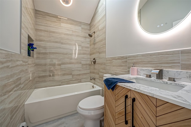 full bathroom featuring toilet, vanity, tile walls, and tiled shower / bath combo