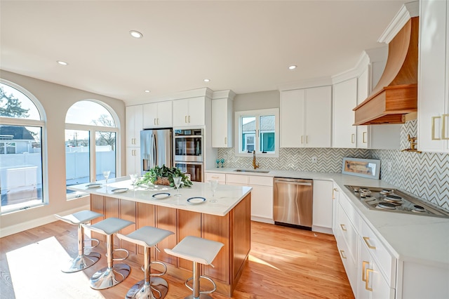 kitchen featuring a kitchen island, stainless steel appliances, custom exhaust hood, and sink