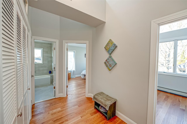 corridor featuring a baseboard radiator and light hardwood / wood-style floors