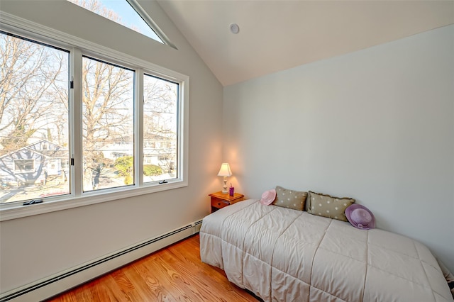 bedroom featuring light wood-type flooring, lofted ceiling, and a baseboard heating unit