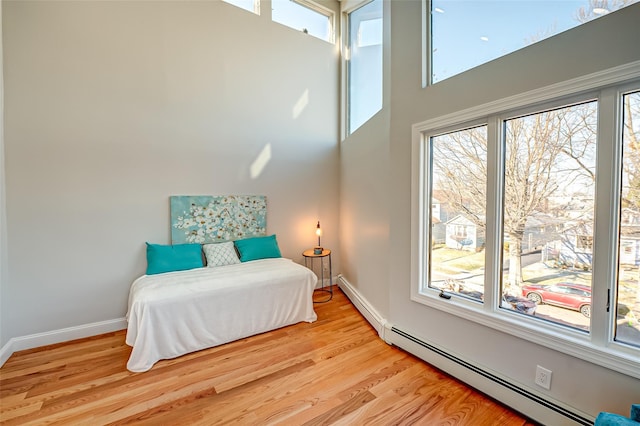 bedroom with baseboard heating and light hardwood / wood-style flooring