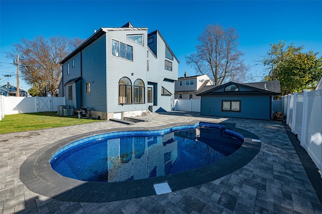 rear view of house with a patio area, central AC unit, a fenced in pool, and an outdoor structure