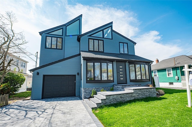 contemporary home with an attached garage, a front lawn, and decorative driveway