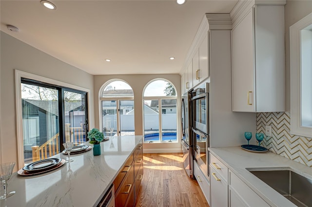 2726 Clarendon Ave, Bellmore, NY 11710 - kitchen with light wood-style floors, decorative backsplash, plenty of natural light, recessed lighting, and light stone counters
